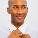 man adjusting his tie with a confident smile looking right