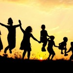 silouettes of 7 children jumping against a sunset or sunrise background